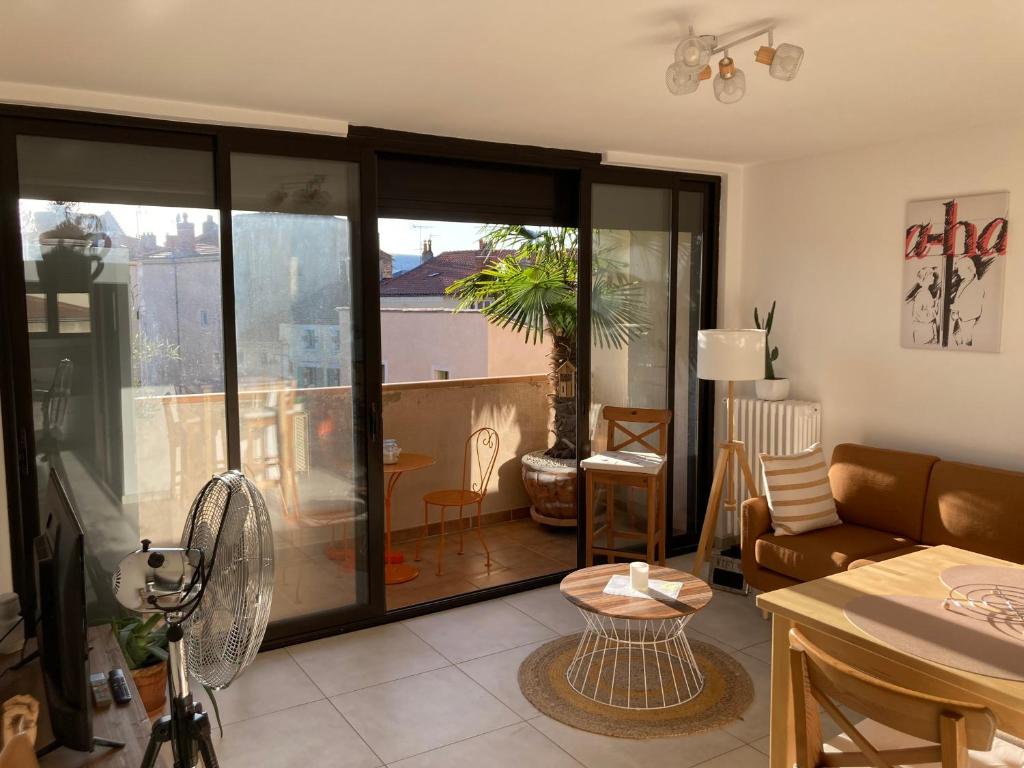 ein Wohnzimmer mit einem Sofa und einem Tisch in der Unterkunft L’appartement du bonheur in Issoire