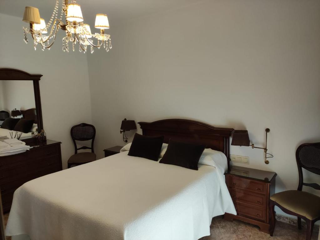 1 dormitorio con cama blanca y lámpara de araña en LA DESCALZA en Lucena