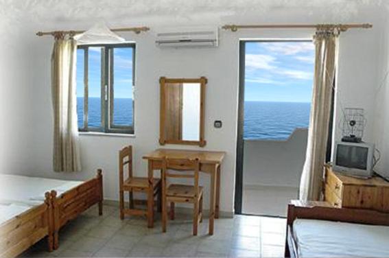 a bedroom with a table and chairs and a room with the ocean at Nitsa Rooms in Kos