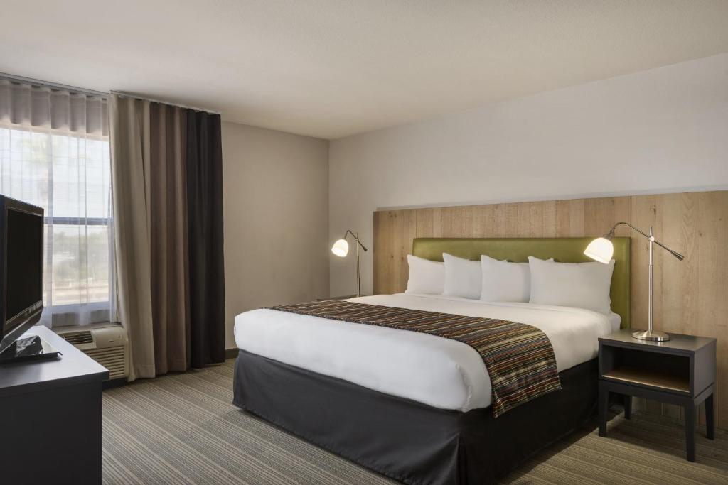 Una habitación de hotel con una cama grande y un televisor. en GreenTree Inn &amp; Suites Phoenix Sky Harbor, en Phoenix