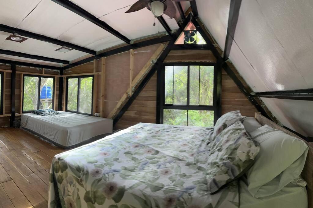 a bedroom with a bed in a room with windows at Aqeel cabin in the nature in Penonomé