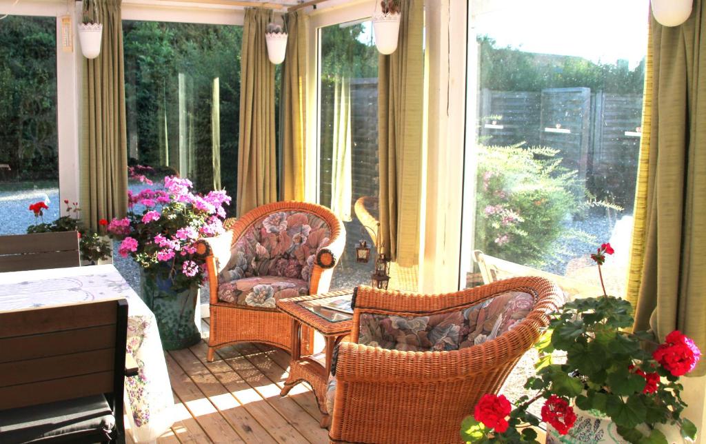 a screened in porch with two chairs and flowers at Hine Bakke Bed And Breakfast in Rudkøbing