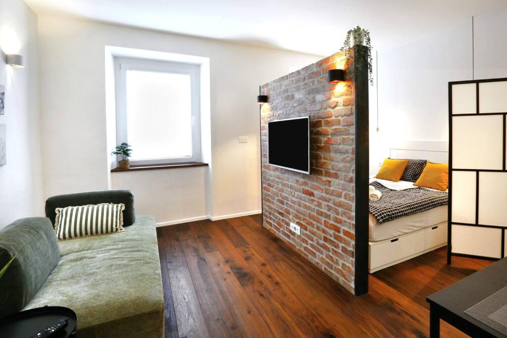 Wally apartment في ليوبليانا: غرفة معيشة مع جدار من الطوب وأريكة
