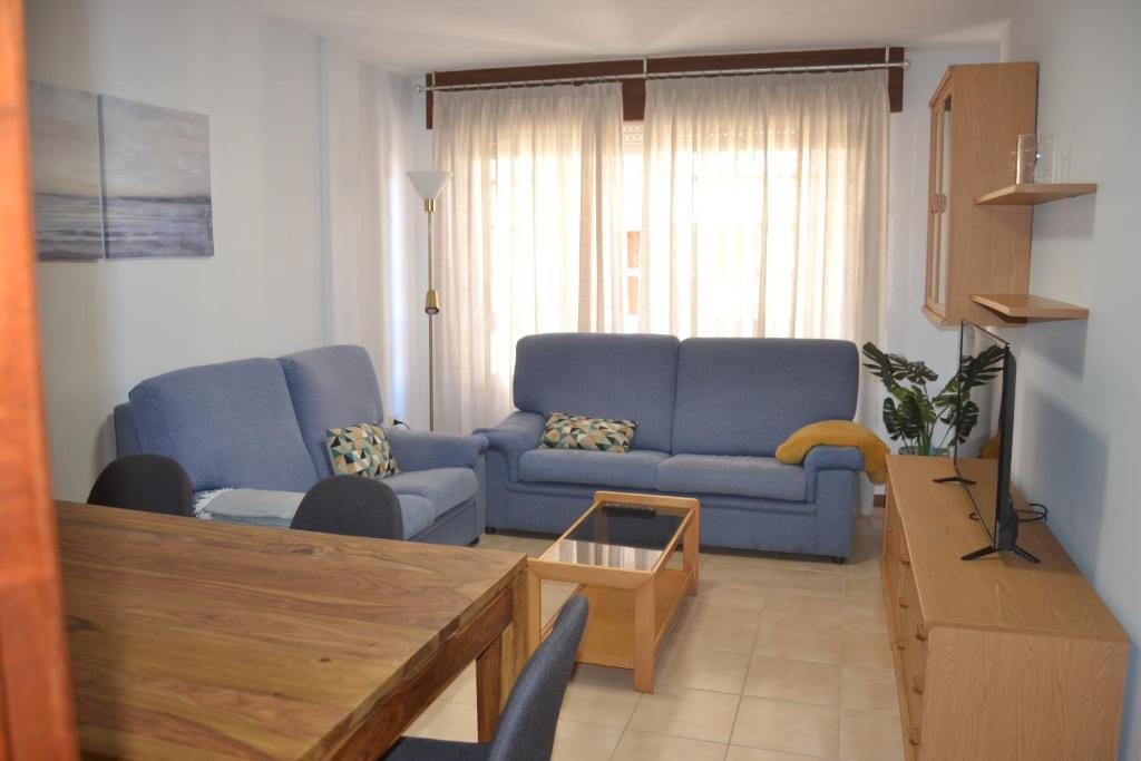 un soggiorno con divano blu e tavolo di Apartamento Puente a Portonovo