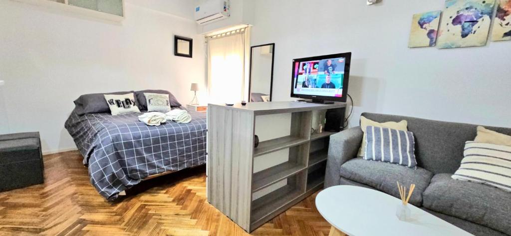 sala de estar con cama, TV y sofá en Super ambiente en el corazón de Buenos Aires en Buenos Aires