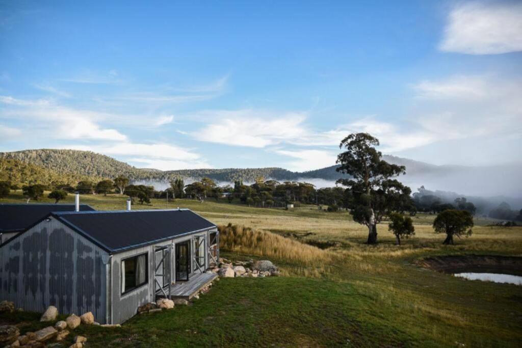 a tiny house in a field with a tree at Tinkersfield's Field Houses in Crackenback