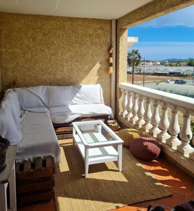 a room with a bed and a table on a balcony at Appartement de charme proche de la mer in Hyères