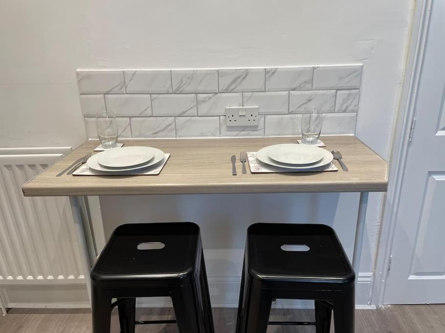 a table with two chairs and a table with plates and glasses at Large, stylish 2bedroom apartment l free parking in Elswick