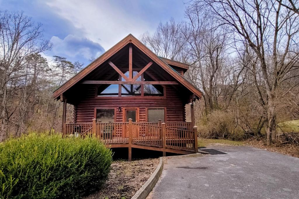 a log cabin in the woods with a large deck at Jolene Jolene in Pigeon Forge