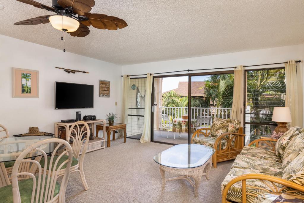 a living room with a couch and a table with a television at Sea Village #3202 in Kailua-Kona