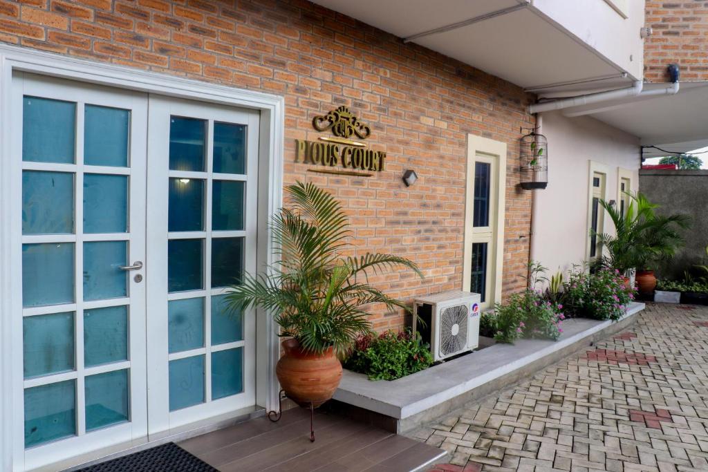 ein Backsteingebäude mit einem Hausguru-Schild und Pflanzen in der Unterkunft Pious Court in Port Harcourt