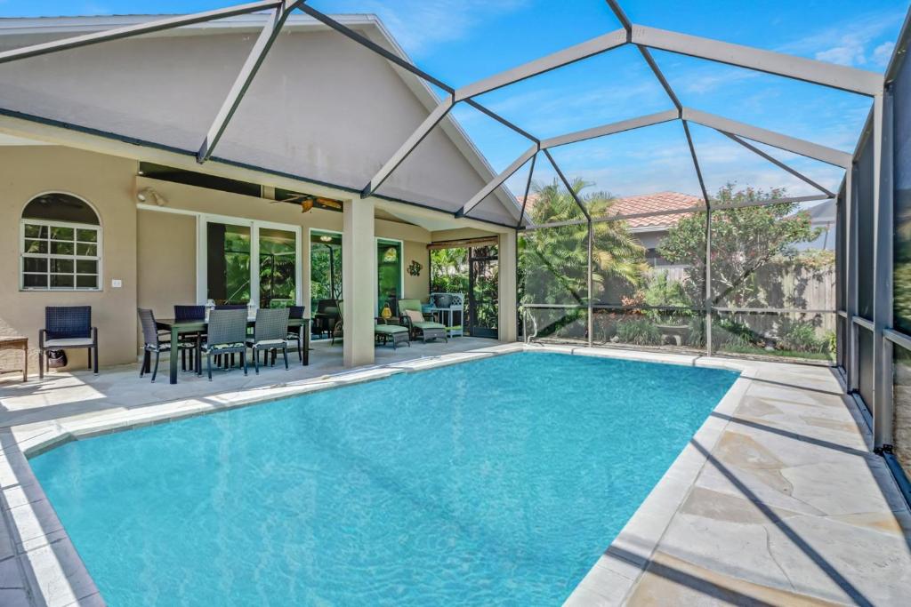 une piscine avec une grande extension en verre jusqu'à une maison dans l'établissement Cozy Beach House - 5 minutes from Vanderbilt Beach, à Naples