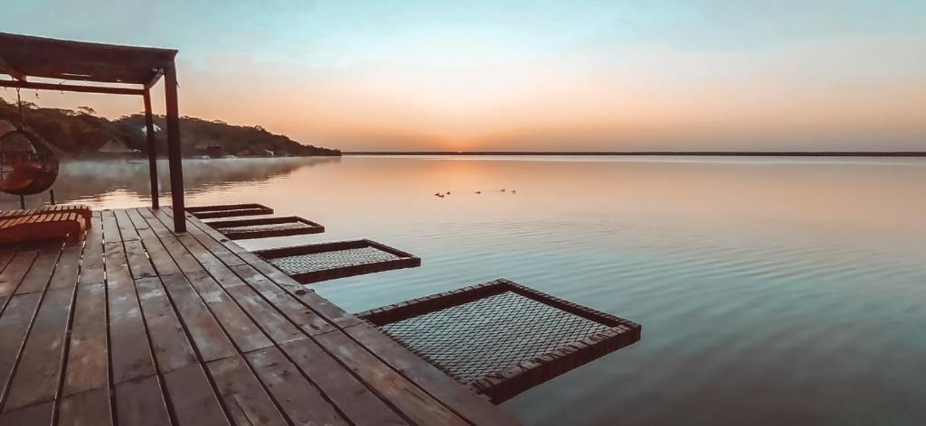 a dock with a view of a lake at sunset at MBH Maya Bacalar Hotel Boutique in Bacalar