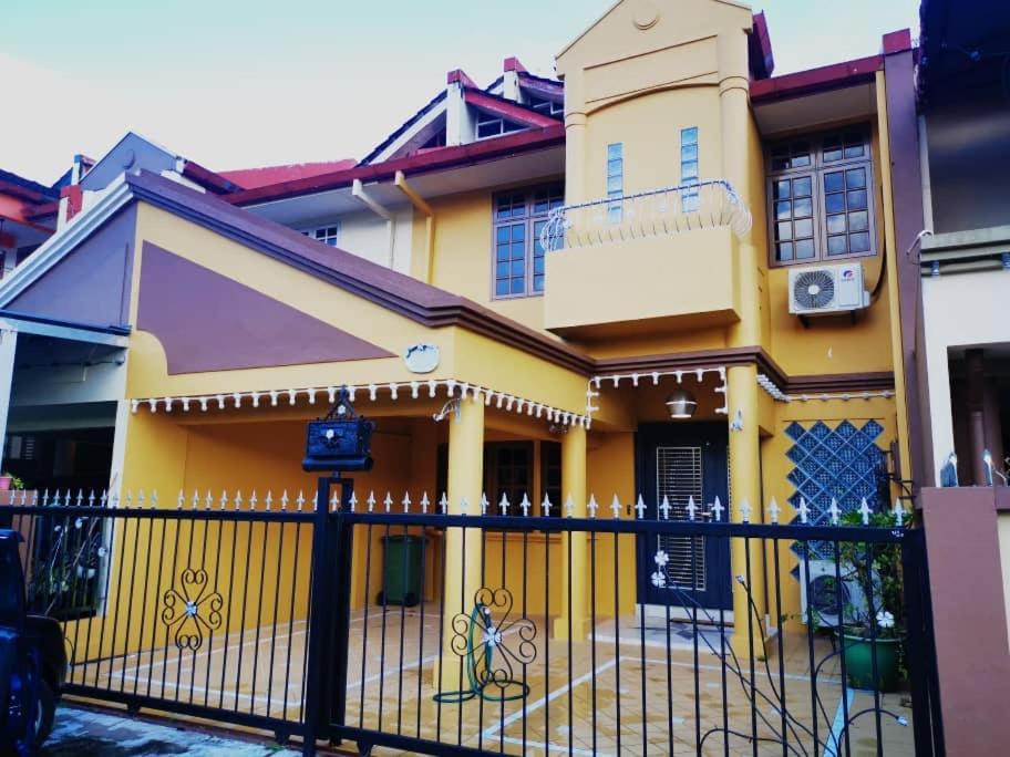 een geel huis met een zwart hek bij Iman Homestay: Sri Kandis in Kuching