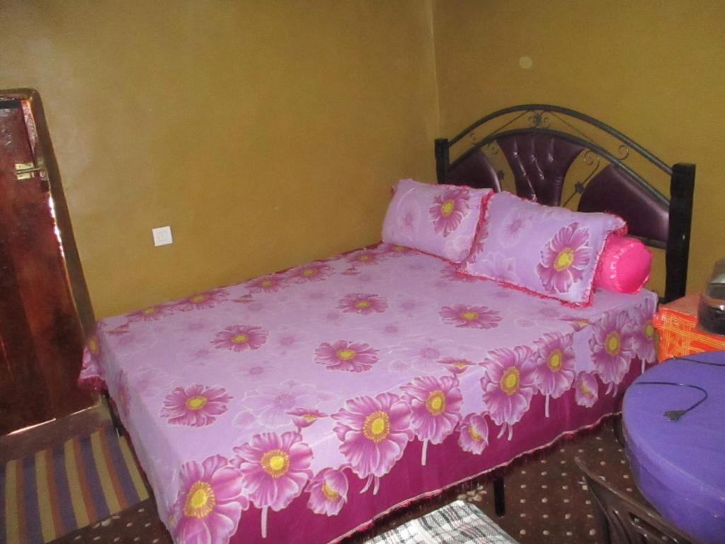 Un dormitorio con una cama rosa con flores. en DAR Awlim en Annoums