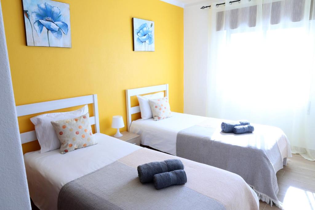 2 letti in una camera con pareti gialle di Apartamento - Férias Felizes Portimão a Portimão