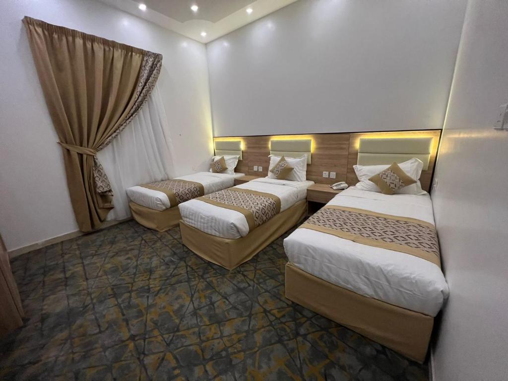 a hotel room with three beds and a window at فندق ريسان in Al Madinah