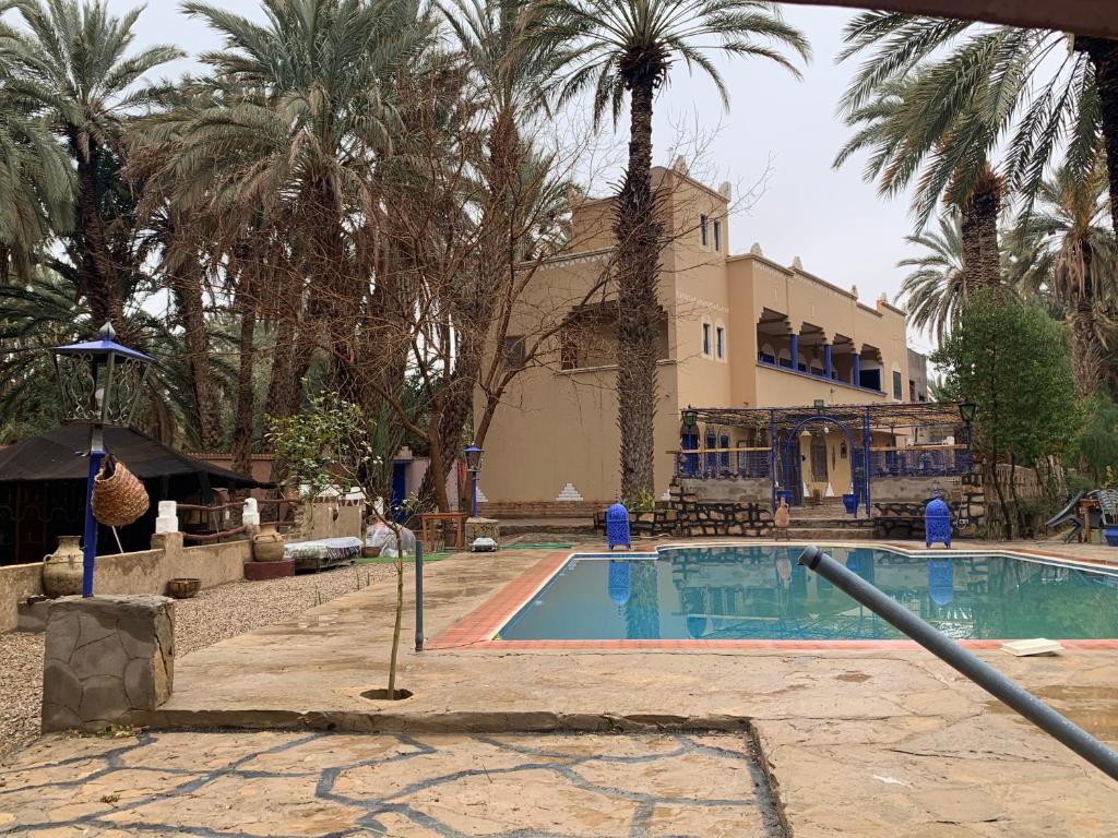 a swimming pool in front of a building with palm trees at Gite D'Etape Amced in Goulmima