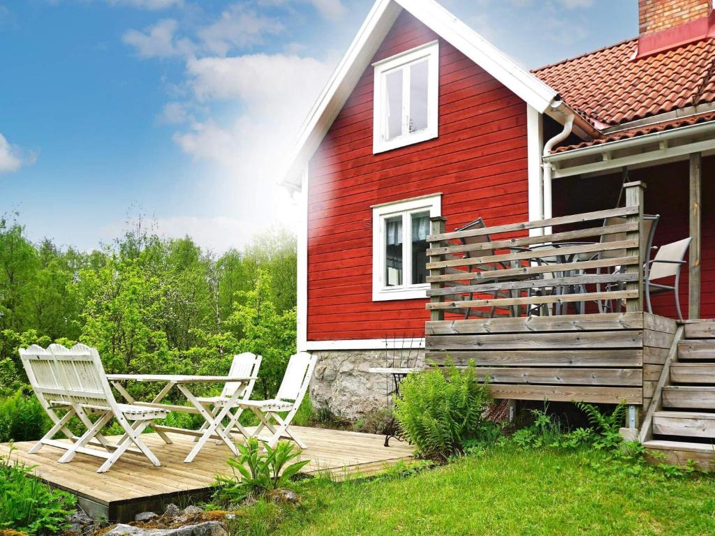 a red house with chairs and a table on a deck at 6 person holiday home in HALLABRO-By Traum in Hallabro