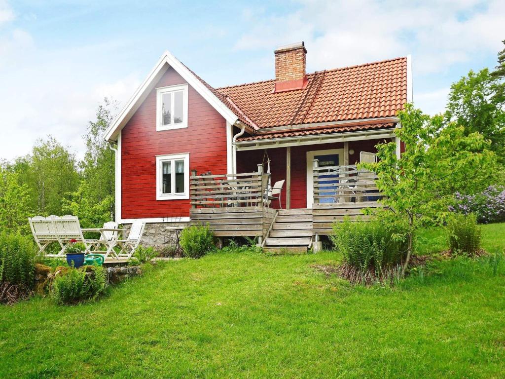 a red house with a deck and two chairs at Holiday home HALLABRO IV in Hallabro