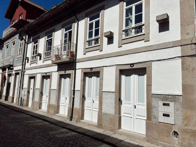 un edificio con puertas y ventanas blancas en una calle en Centro da Vila, en Ponte de Lima
