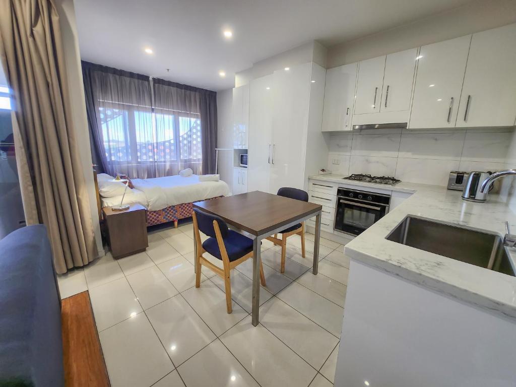 a kitchen with a table and a room with a bed at Exodus Dandenong Apartment Hotel in Dandenong