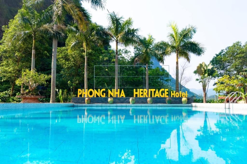 une piscine avec des palmiers en arrière-plan dans l'établissement Heritage By Night, à Lang Va