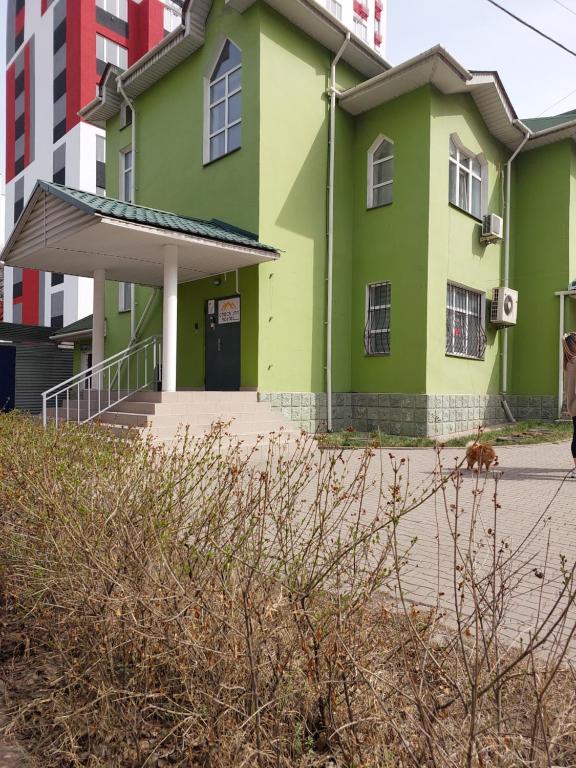 a green building with a dog in front of it at Check Inn Hostel in Almaty