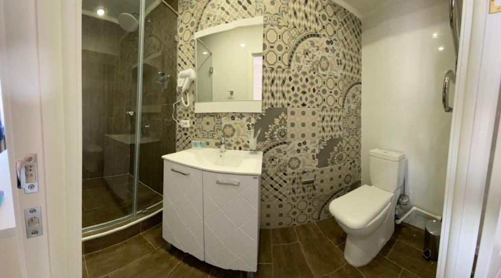 e bagno con servizi igienici, lavandino e doccia. di De Marco Hotel a Qostanay