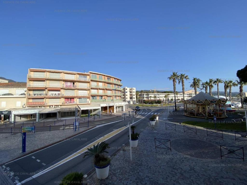 une rue vide avec un bâtiment et des palmiers dans l'établissement Appartement T2 avec Terrasse et Garage à Cavalaire-sur-Mer - Proche Port - FR-1-100-262, à Cavalaire-sur-Mer