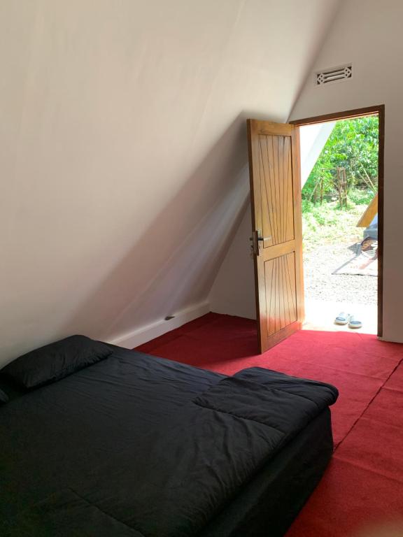 a bedroom with a bed and an open door at Jambusari Ijen Crater Cottage in Jambu