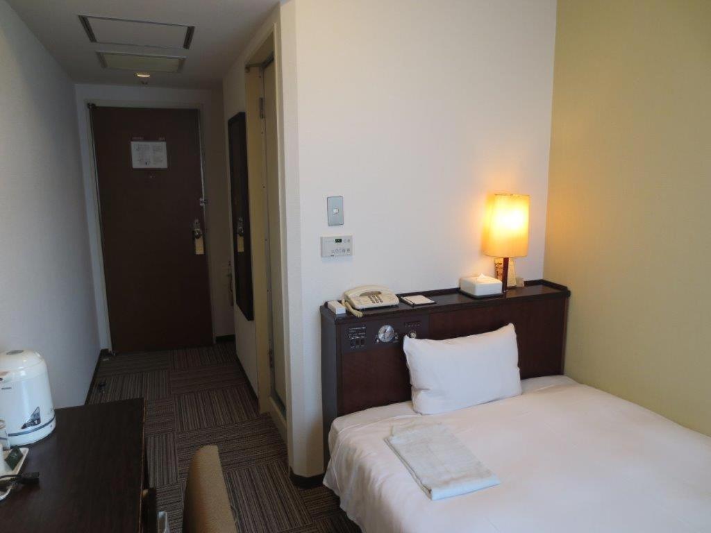 Habitación de hotel con cama con lámpara. en Nest Hotel Kumamoto en Kumamoto