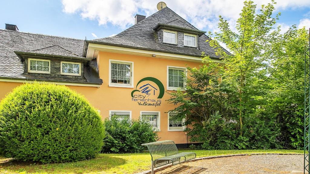 une maison jaune avec un banc devant elle dans l'établissement City Ferienhaus Vulkaneifel, à Daun