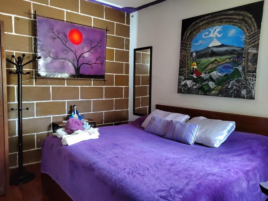 1 dormitorio con cama morada y pared de ladrillo en Temazcal Hospedaje "gema" adults only, en Tepoztlán
