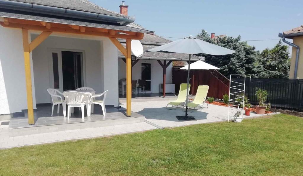 un patio avec une table, des chaises et un parasol dans l'établissement Holiday home in Balatonkeresztur 44078, à Balatonkeresztúr