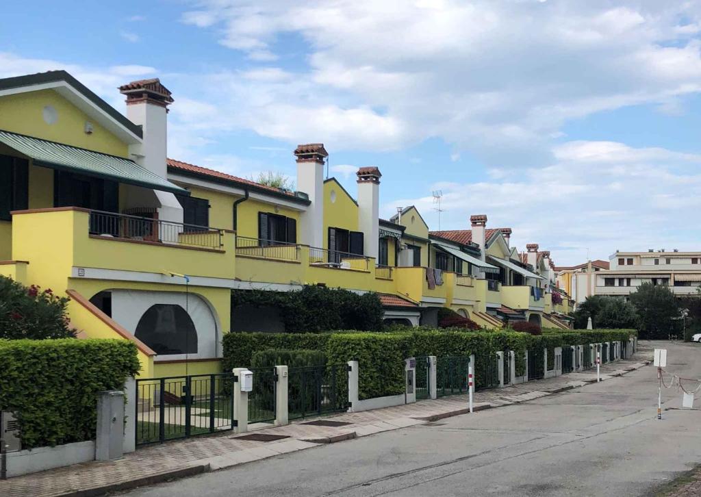 uma fila de casas amarelas ao lado de uma rua em Apartments in Eraclea 44135 em Eraclea