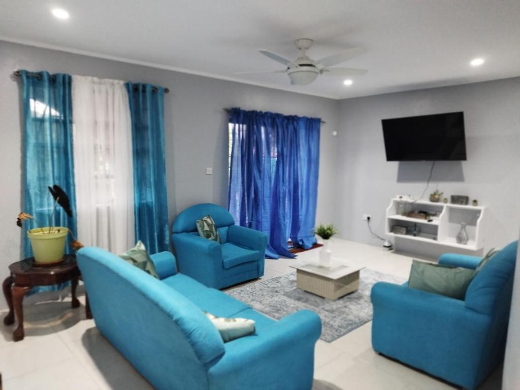 een woonkamer met blauwe stoelen en een flatscreen-tv bij Arcadia House in Vieux Fort