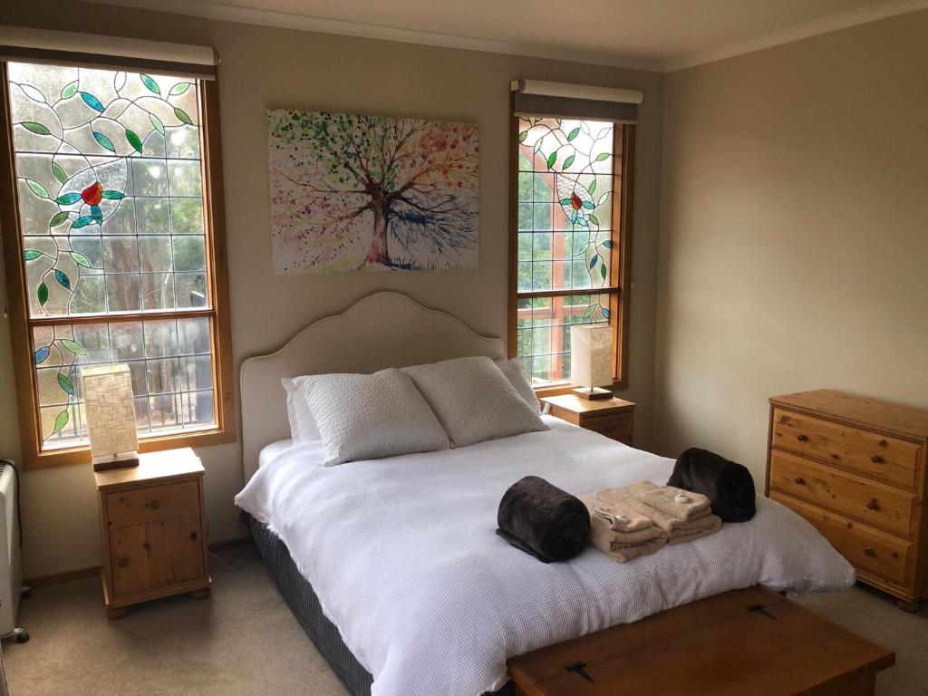 a bedroom with a white bed with stained glass windows at Day Dream Cottage in Merrijig