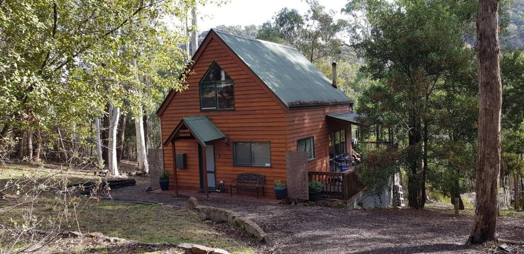 uma pequena cabana de madeira na floresta em Kookas Cottage em Merrijig