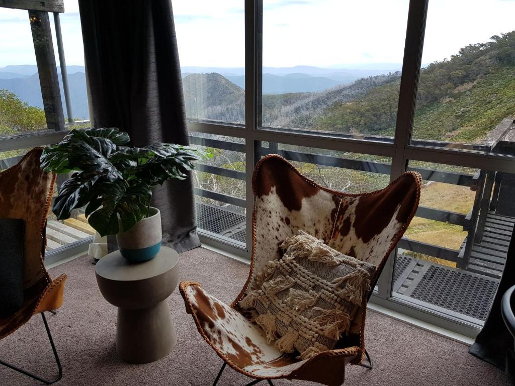 um quarto com uma grande janela com cadeiras e uma planta em SKI View 1 em Mount Buller