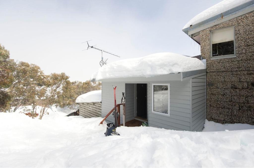 a house covered in snow next to a building at SKI View 4 in Mount Buller