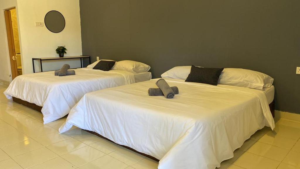 2 bedden in een kamer met witte lakens bij Bayu Cenang Inn in Pantai Cenang