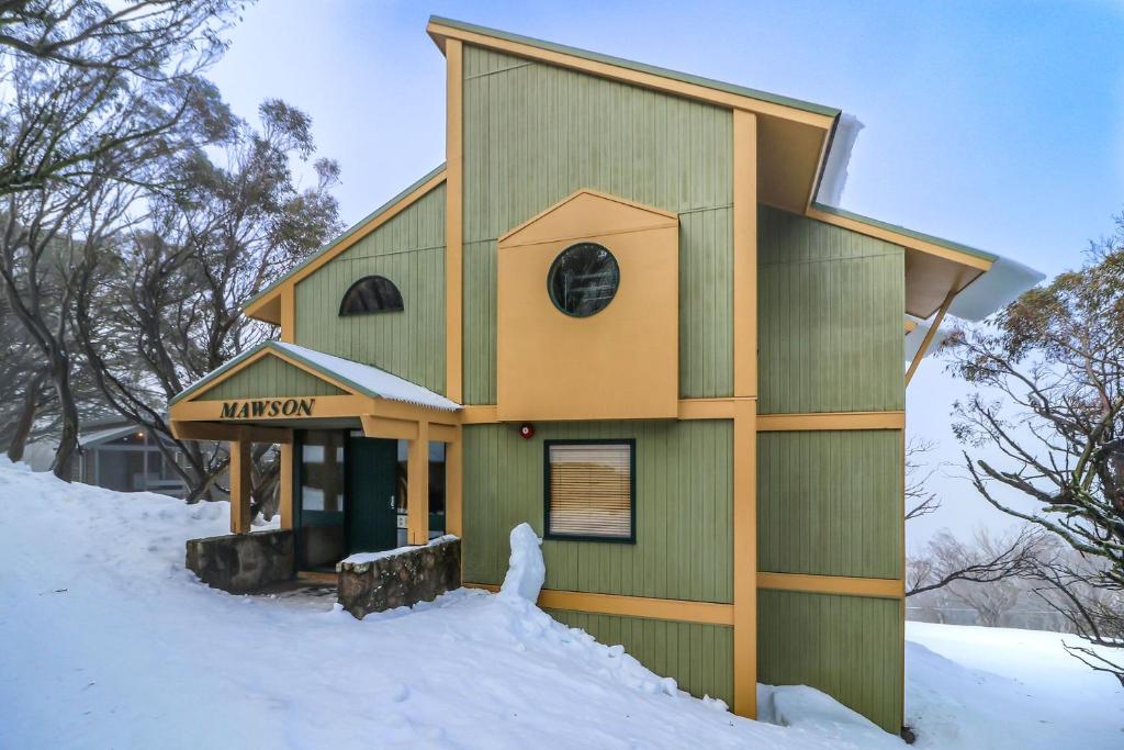 a small green building in the snow at Mawson 5 in Mount Buller