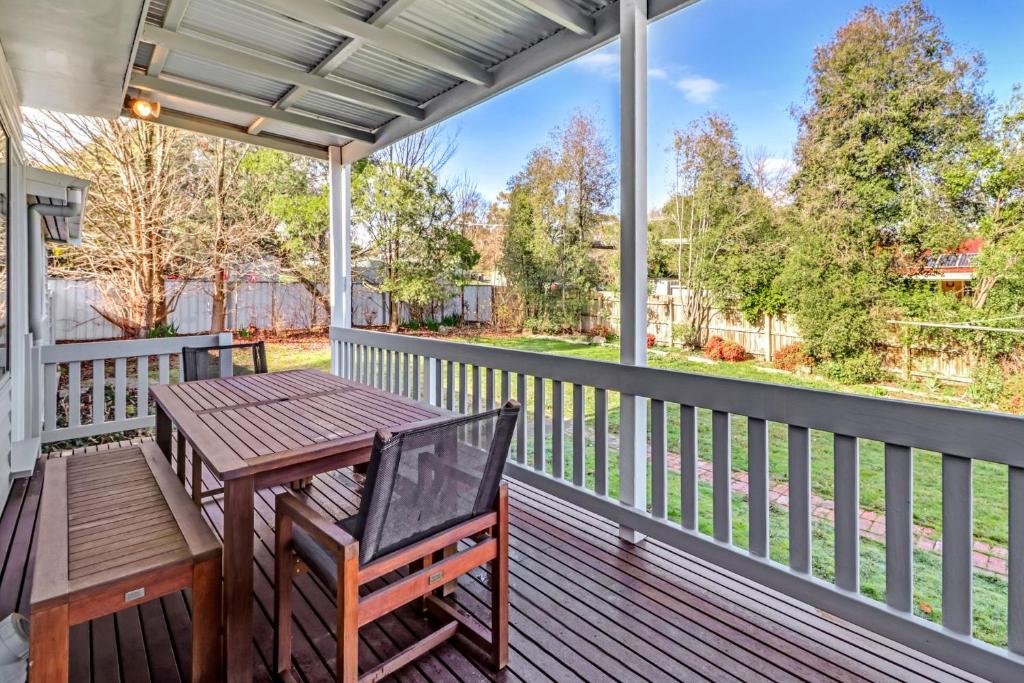 une terrasse couverte avec une table en bois et un banc dans l'établissement Elouera, à Mansfield