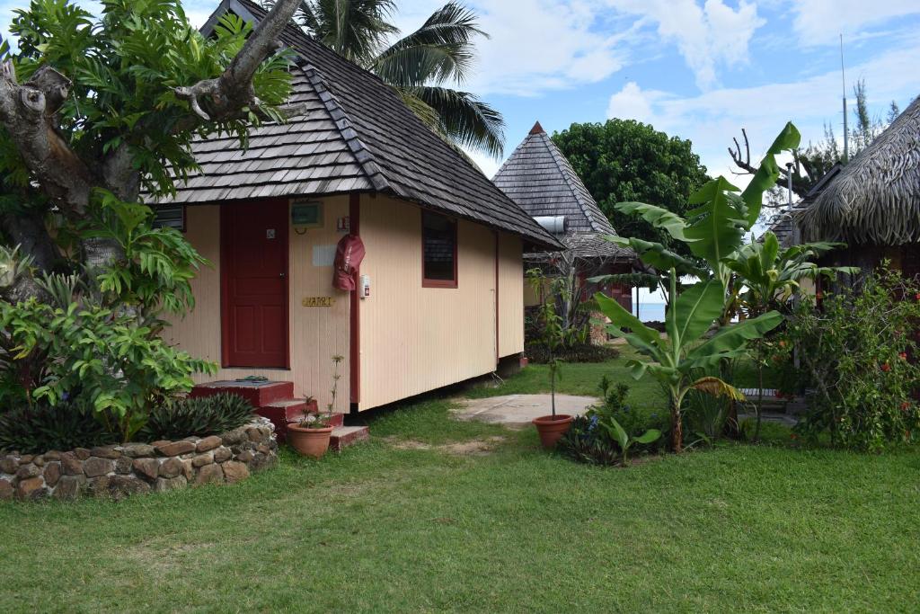a small house with a red door in a yard at Fare Aute Beach in Vaianae