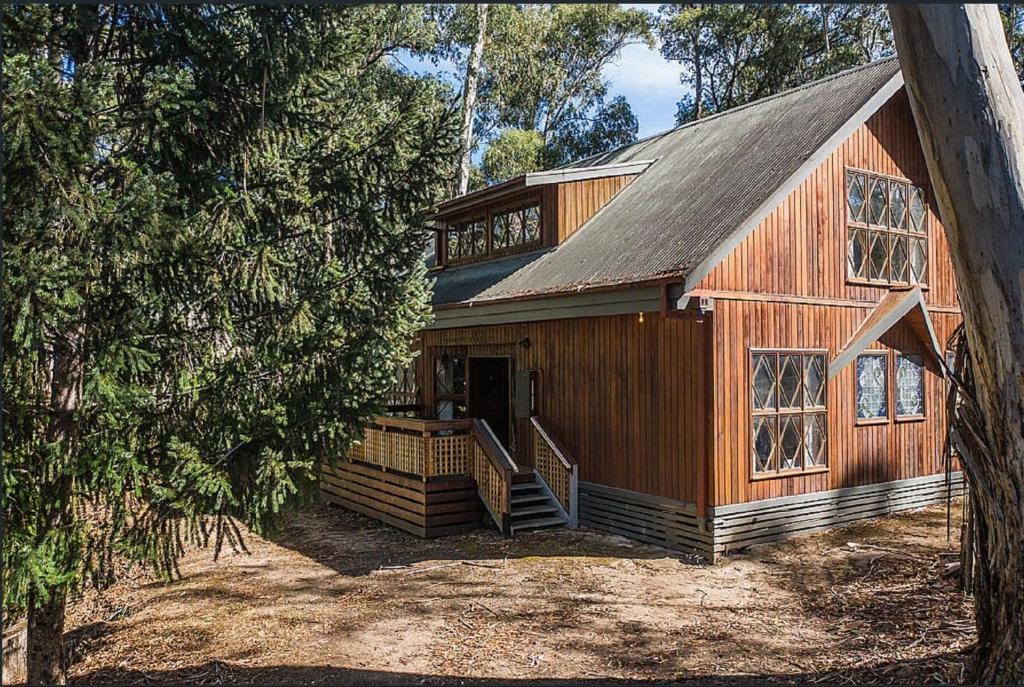 a large wooden house in the middle of a forest at Lumi Talo in Merrijig