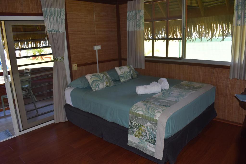 a bedroom with a bed in a room with windows at Fare Aute Beach in Vaianae