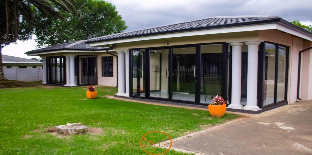 a house with large glass doors on a yard at Slee Guest House in Howick