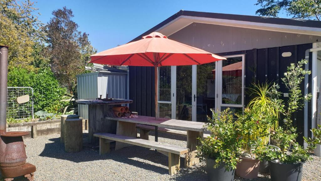 a picnic table with an umbrella in front of a shed at Diamond Retreat in Tairua