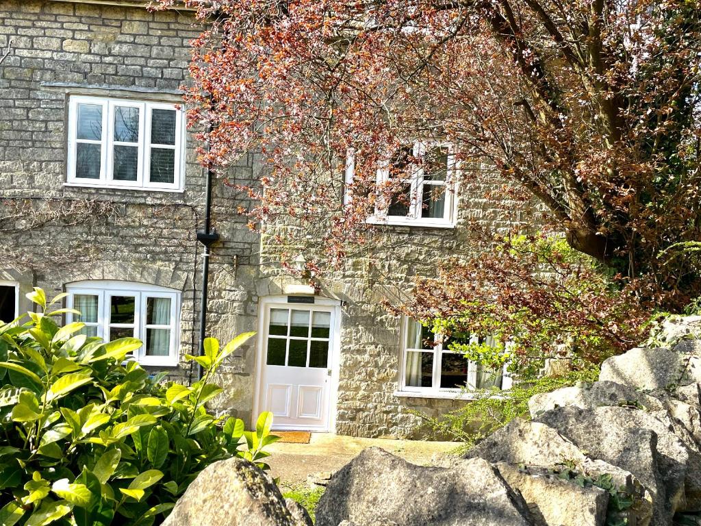 a stone house with a white door and windows at The Garden Cottage in Stroud